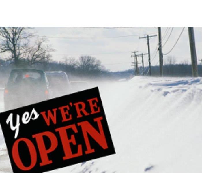 snow covered road, vehicles, power lines, sign wording yes we are open